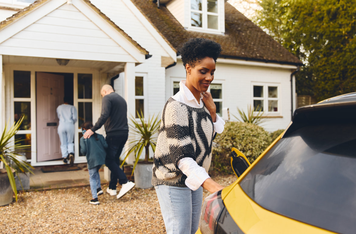 Woman charging electric car on driveway